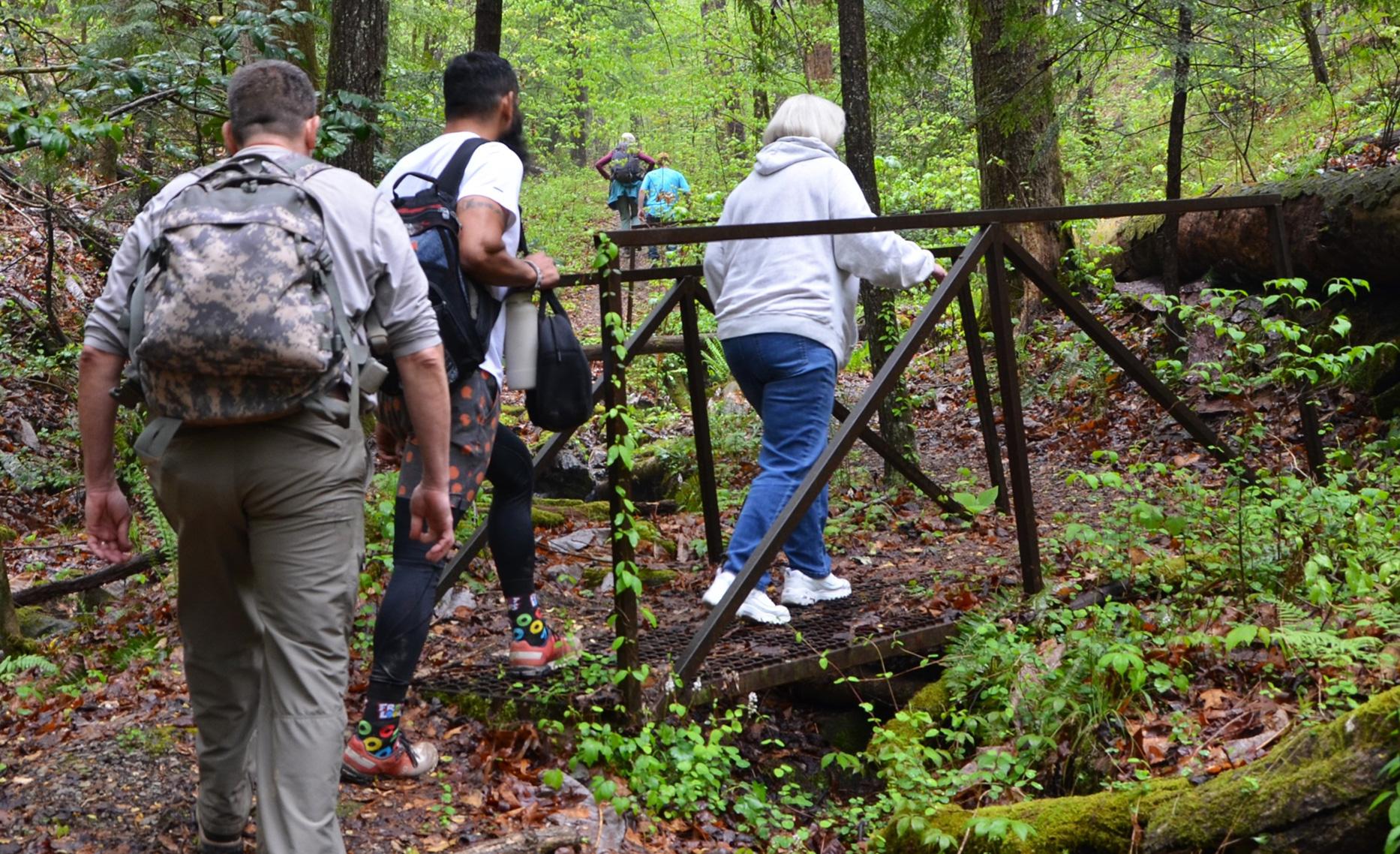Joel Cruz and fellow walkers crossing a footbridge on a forest trail in Bankhead National Forest